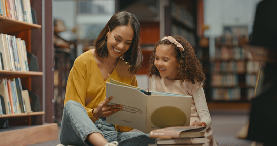 mother and daughter in the library reading a book